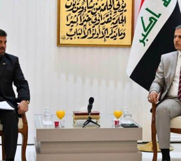 مسؤولان عراقي وإيراني خلال اجتماع أمني بحضور العلم العراقي 