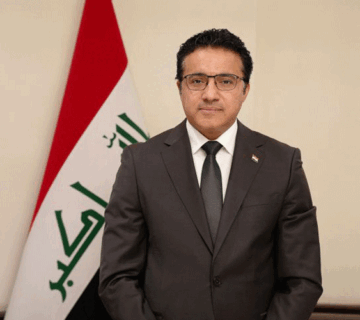 حيدر العبودي يقف أمام العلم العراقي 