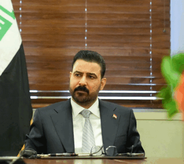 رئيس الوزراء العراقي يجلس أمام العلم العراقي خلال اجتماع رسمي 