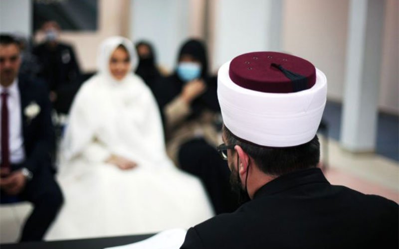 مأذون شرعي أثناء مراسم عقد القِران بحضور العروسين والعائلة 