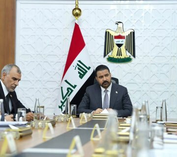 اجتماع رسمي لمسؤولين عراقيين بحضور العلم وشعار الجمهورية العراقية 
