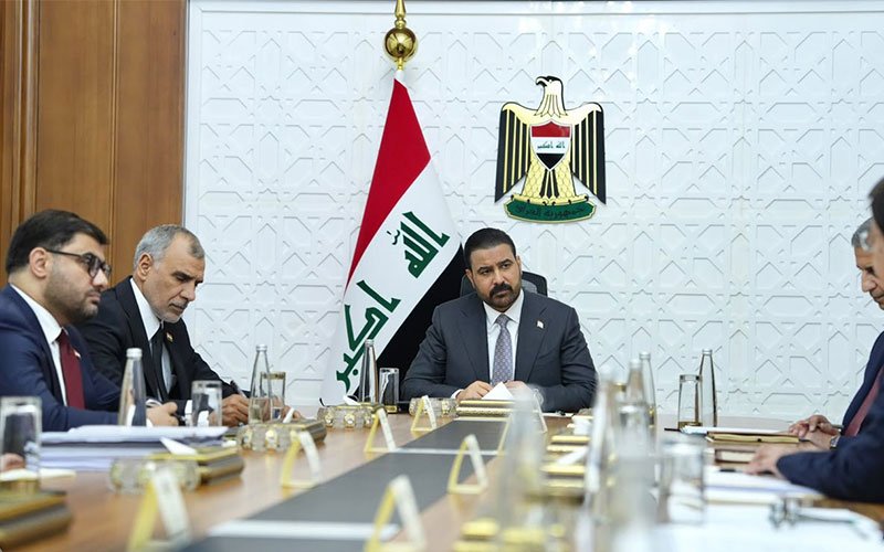 اجتماع رسمي لمسؤولين عراقيين بحضور العلم وشعار الجمهورية العراقية 