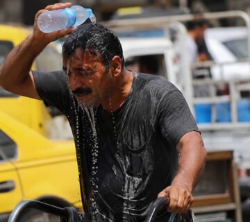 رجل يسكب الماء على رأسه للتخفيف من شدة الحر في أحد شوارع العراق 