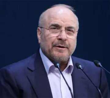 صورة بورتريه لرئيس مجلس الشورى الإيراني محمد باقر قاليباف يرتدي بدلة داكنة وينظر للأمام أثناء حديثه خلف الميكروفونات 