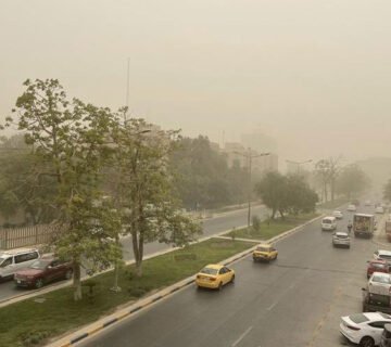 شارع في مدينة عراقية تسوده أسباب الرؤية المنخفضة بسبب الغبار في السماء 