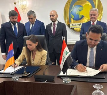 ممثلان عن حكومتي العراق وأرمينيا يوقعان مذكرتي تفاهم على طاولة اجتماع أمام علمي البلدين وشعار وزارة الخارجية العراقية في الخلفية 