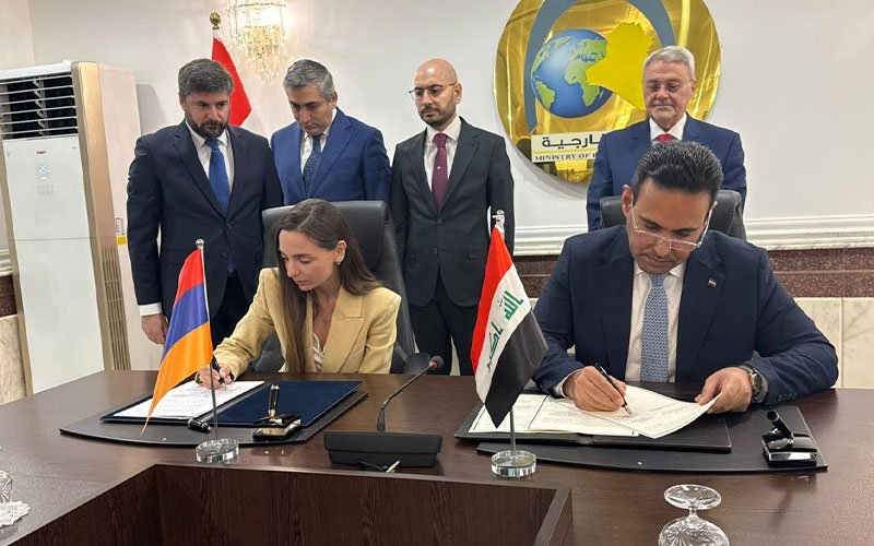 ممثلان عن حكومتي العراق وأرمينيا يوقعان مذكرتي تفاهم على طاولة اجتماع أمام علمي البلدين وشعار وزارة الخارجية العراقية في الخلفية 