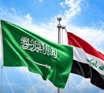 العلمان العراقي والسعودي يرفرفان جنباً إلى جنب تحت سماء زرقاء 