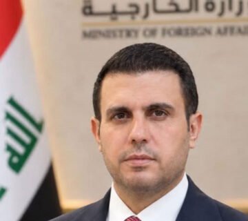 المتحدث باسم وزارة الخارجية العراقية أمام شعار الوزارة والعلم العراقي 