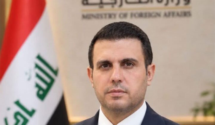المتحدث باسم وزارة الخارجية العراقية أمام شعار الوزارة والعلم العراقي.