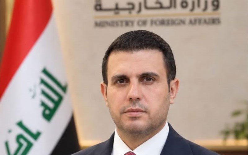 المتحدث باسم وزارة الخارجية العراقية أمام شعار الوزارة والعلم العراقي 